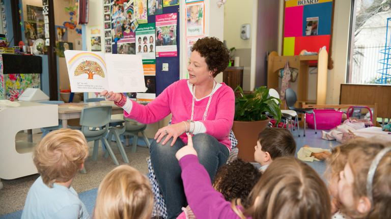  An early childhood teaching student reading to children in the classroom.